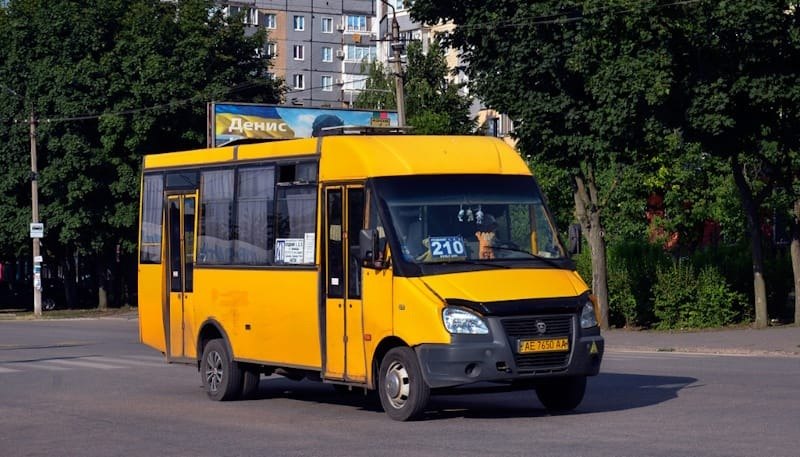Жовта маршрутка з номером 210 на лобовому склі їде дорогою