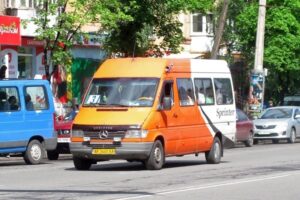Помаранчево-біла маршрутка Mercedes Sprinter з номером 3 на табло рухається дорогою в Кривому Розі.