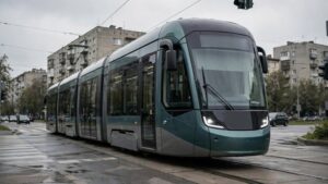 Сучасний трамвай зеленого кольору на вулиці міста в похмуру погоду