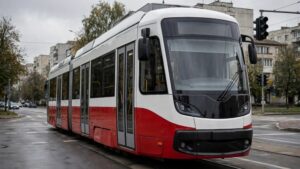 Сучасний трамвай червоно-білого кольору на вулиці міста в похмуру погоду