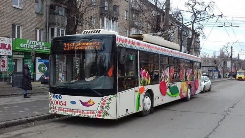 Тролейбус з номером 21 на табло стоїть на зупинці біля житлового будинку.