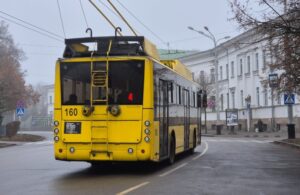 Жовтий тролейбус ззаду на дорозі
