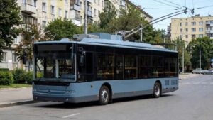 Сірий тролейбус на вулиці міста, на фоні житлових будинків