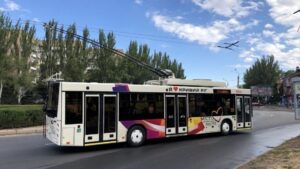 Білий тролейбус з яскравим візерунком та написами «Я люблю Кривий Ріг» та «Місто довжиною в життя» їде дорогою.