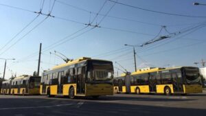 Три жовті тролейбуси на стоянці під відкритим небом.
