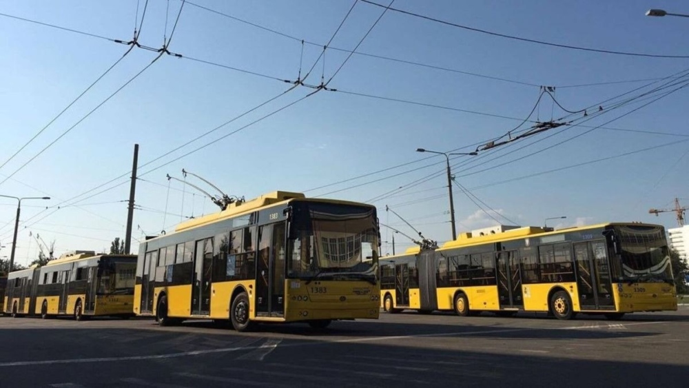 Три жовті тролейбуси на стоянці під відкритим небом.